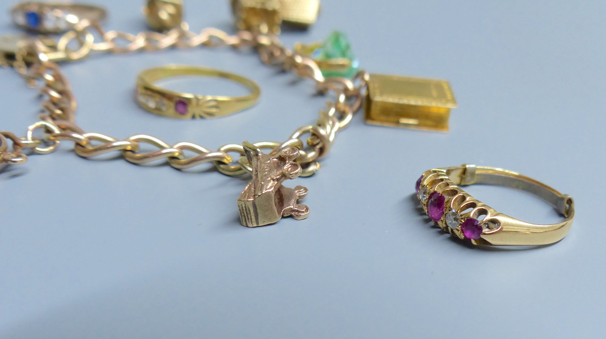 A 9ct gold charm bracelet, hung with six assorted charms including 9ct gold and 3 rings.